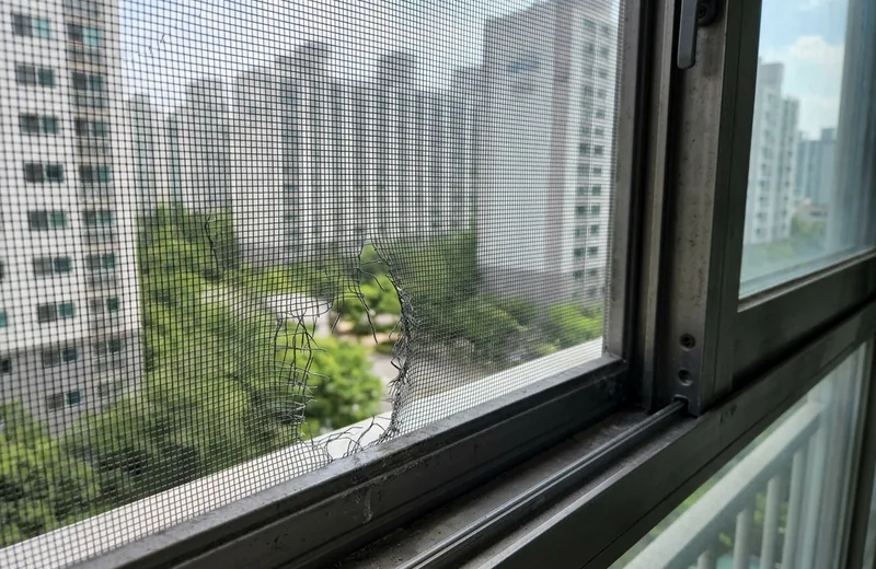 모서리가 찢어지고 손상된 아파트 베란다 방충망