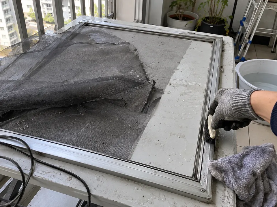 분리한 방충망 프레임에서 노후 망을 걷어내고 고무 가스켓 홈을 청소하는 모습
